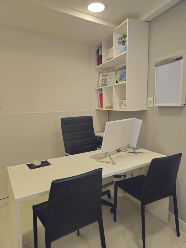 Consultório com mesa, computador e estante
